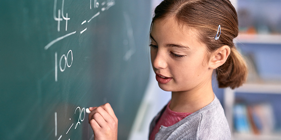 Menina fazendo conta de matemática no quadro com giz 