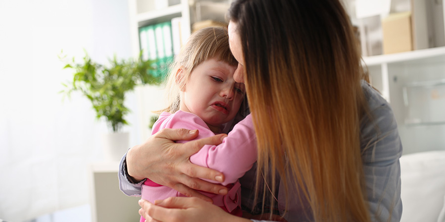 menina no colo da mãe chorando 
